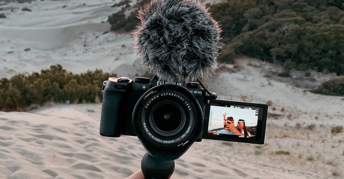 Vlogger recording at sunset on a sandy beach using a handheld camera with a microphone.